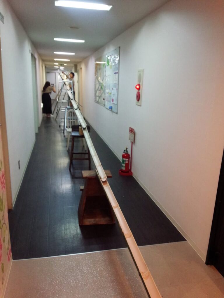 シェアハウスの廊下に竹で組んだ流しそうめんの装置